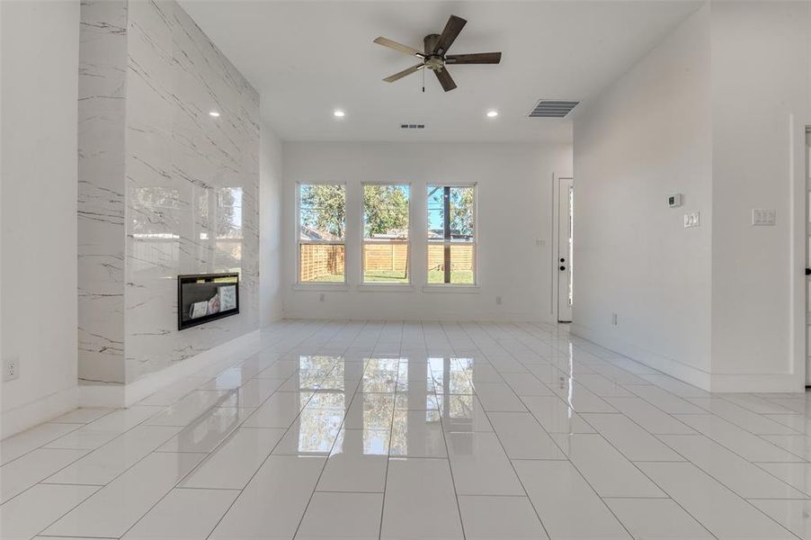 Unfurnished living room with a fireplace, ceiling fan, recessed lighting, and light tile patterned flooring