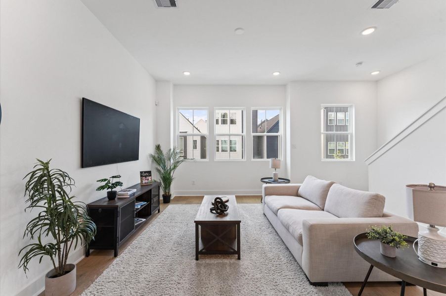 Flooded with natural light, this expansive living area features a wall of oversized windows that frame picturesque views of the lush community courtyard.