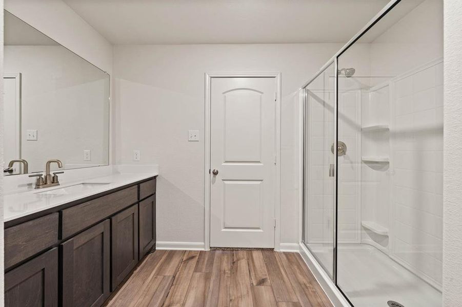 Bathroom with vanity, wood finished floors, a stall shower, and baseboards