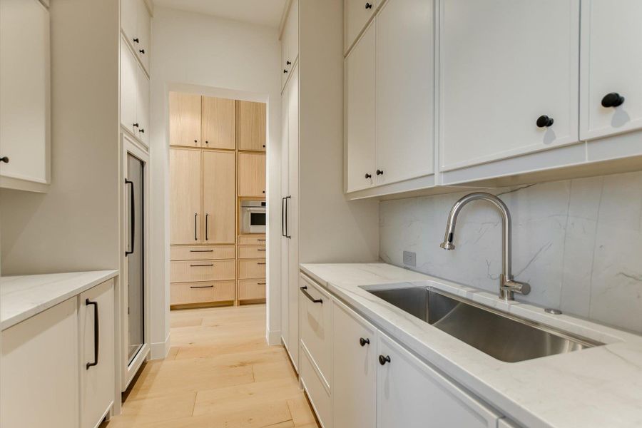 Kitchen with light stone counters, light wood-type flooring, decorative backsplash, and light wood finish cabinetry
