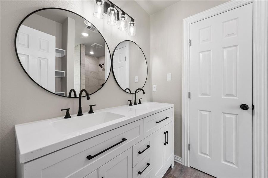 Dual sink vanity featuring matte black hardware, white cabinetry, and quartz countertops