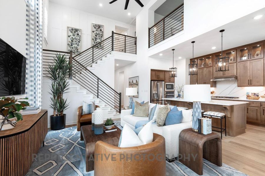 Living room with light wood-style flooring, recessed lighting, a high ceiling, and stairs Living room with light wood-style flooring, recessed lighting, a high ceiling, and stairs