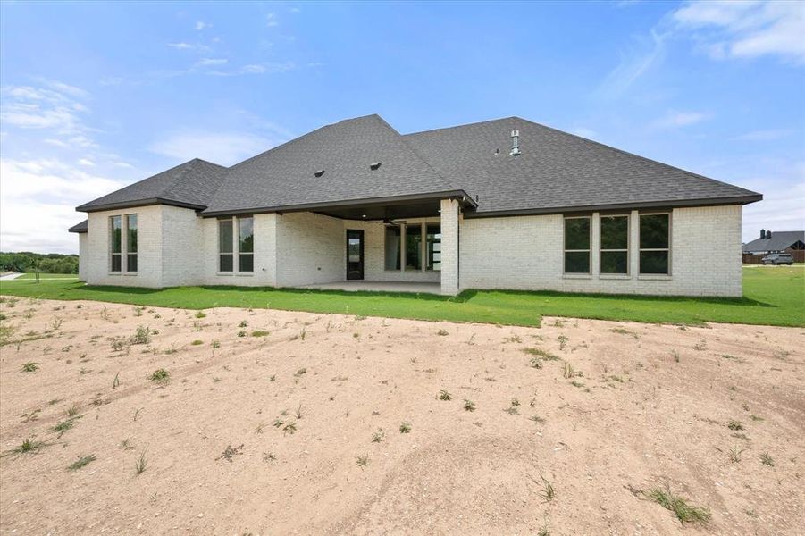 Single-story residence featuring light-colored brick exterior, dark asphalt shingle roof, and multiple large windows with dark trim