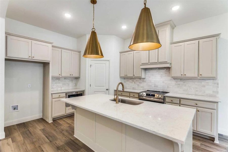 Kitchen featuring light stone counters, sink, decorative light fixtures, and stainless steel electric range oven