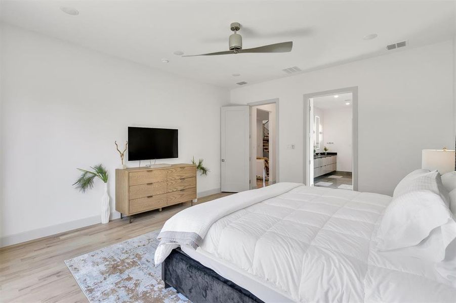 Bedroom with ensuite bathroom, ceiling fan, and light hardwood / wood-style flooring