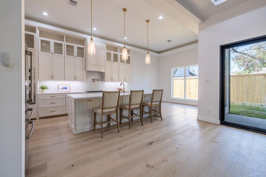 Bright breakfast area framed by large windows and modern lighting, perfect for casual dining.