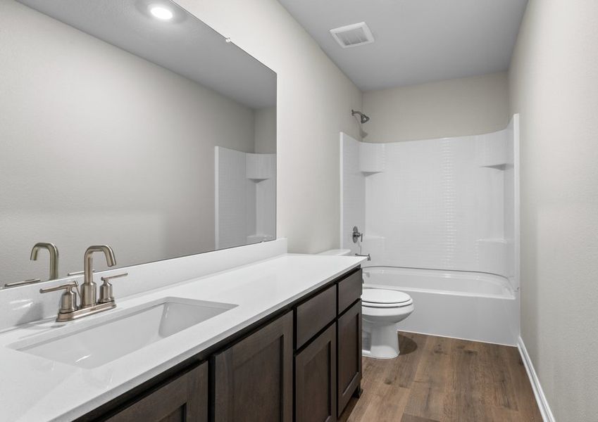The secondary bathroom has a sprawling vanity and a shower-tub combo.