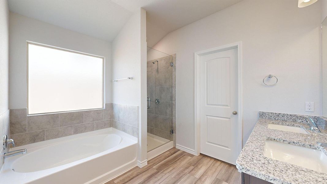 Bathroom featuring a shower stall, a garden tub, double vanity, and light wood-style flooring Bathroom featuring a shower stall, a garden tub, double vanity, and light wood-style flooring