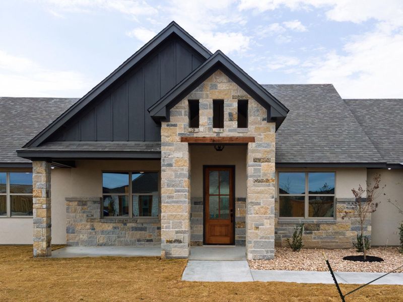 View of front of property with stone siding, board and batten siding, a shingled roof, and stucco siding