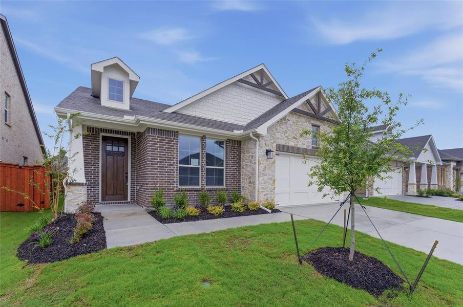 Contemporary residence featuring a brick and stone facade, a two-car garage, and a dormer window