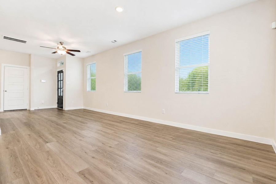 Spacious open-concept living area highlighted by durable wood-look flooring, soft neutral walls, crisp white trim, and an abundance of natural light. Multiple windows enhance the airy atmosphere, while the generous footprint offers flexibility for arranging living, dining, entertaining, or work-from-home spaces. Spacious open-concept living area highlighted by durable wood-look flooring, soft neutral walls, crisp white trim, and an abundance of natural light. Multiple windows enhance the airy atmosphere, while the generous footprint offers flexibility for arranging living, dining, entertaining, or work-from-home spaces.