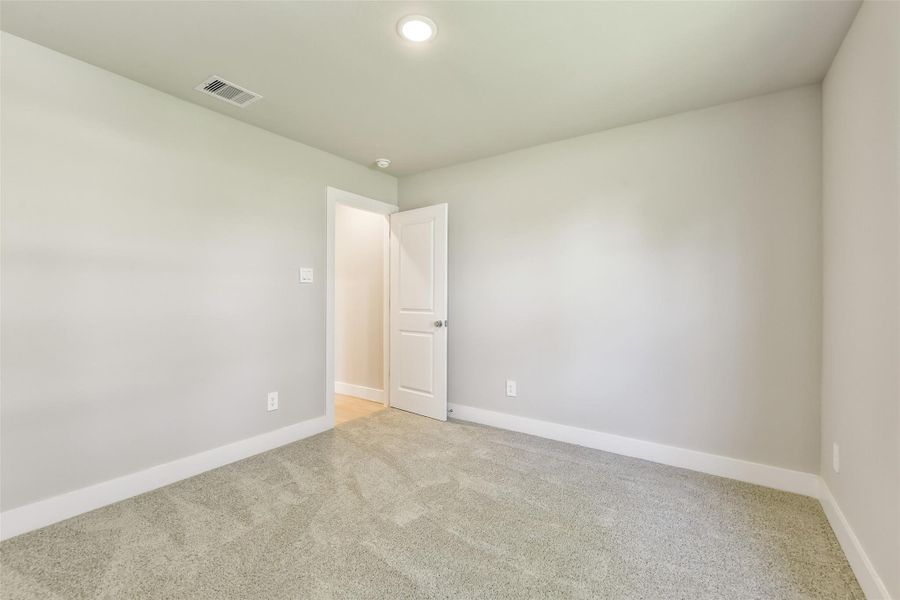 The second secondary bedroom offers a versatile layout with a clean neutral palette and recessed lighting, perfect for a guest room, office or nursery.