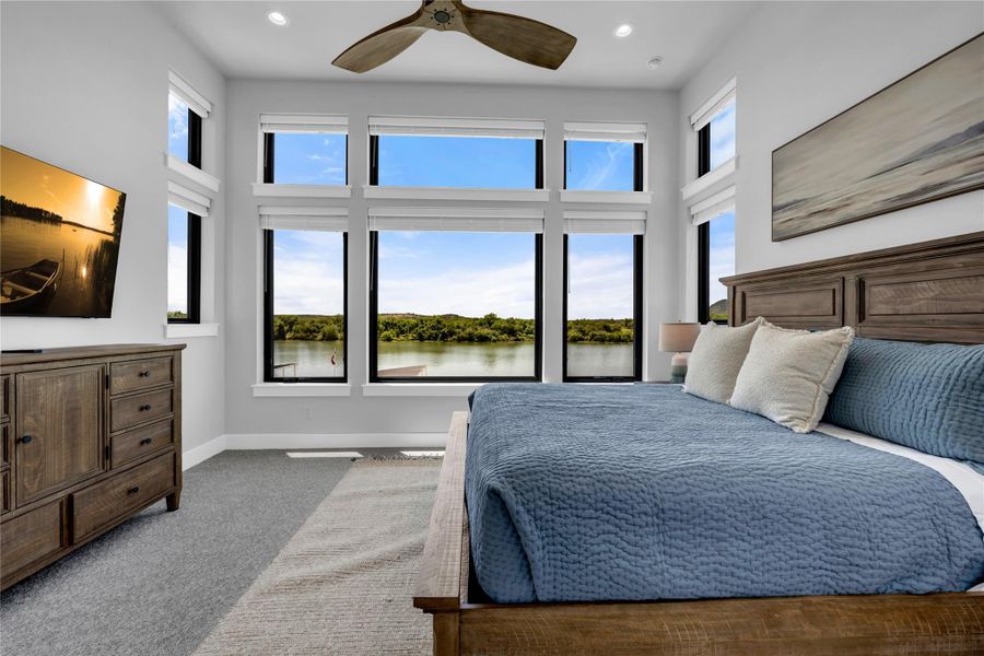 Bedroom two: Bright interior space featuring a multi-paned window wall, recessed lighting, a ceiling fan, and light gray carpeting