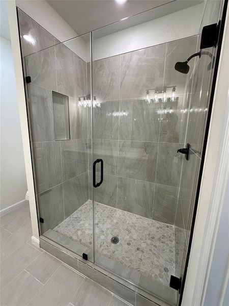 Bathroom featuring a shower with door and tile patterned flooring