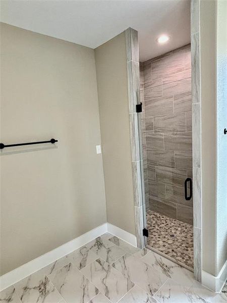 Bathroom with a shower stall, marble look tiles, and recessed lighting Bathroom with a shower stall, marble look tiles, and recessed lighting