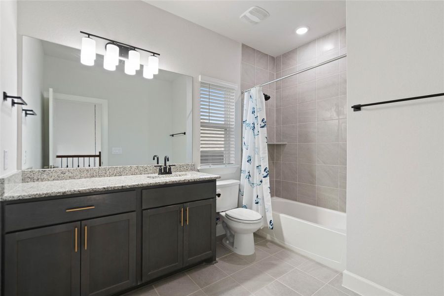 Clean-lined finishes define this modern washroom featuring stone countertops and large-format wall tiles.