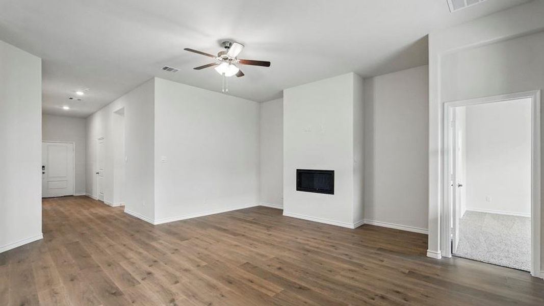 Spacious living area featuring wood-finish flooring, a modern electric fireplace, a ceiling fan with integrated lighting, recessed lighting, and crisp white baseboards