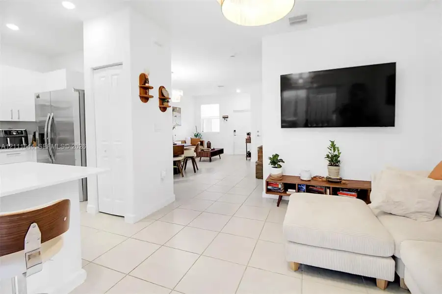 Open-concept floor plan featuring large-format tile flooring, white cabinetry, integrated stainless steel appliances, and recessed lighting Open-concept floor plan featuring large-format tile flooring, white cabinetry, integrated stainless steel appliances, and recessed lighting