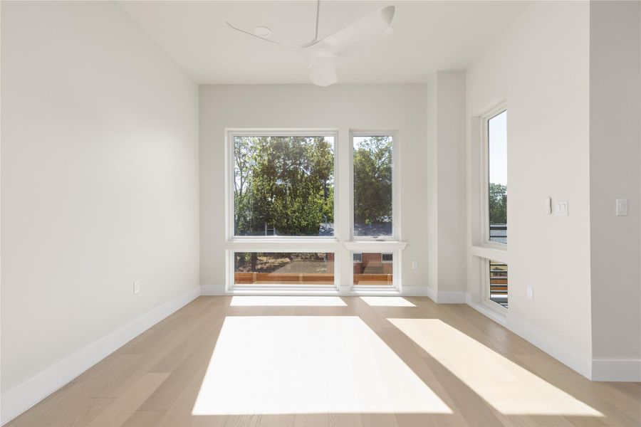 Crisp white walls and light wood flooring frame leafy views through large windows.