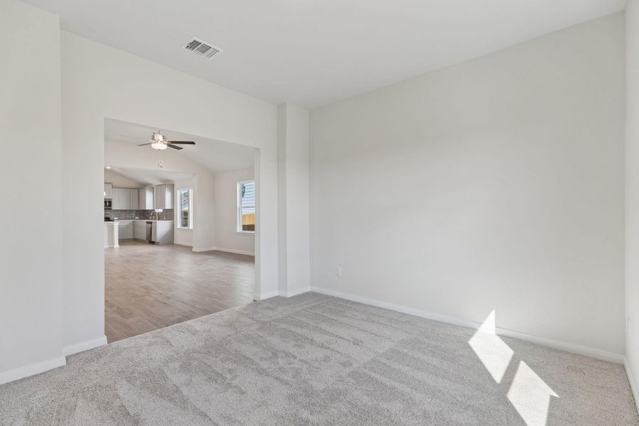 An open archway connects soft carpeted floors to the light-filled main living spaces beyond.