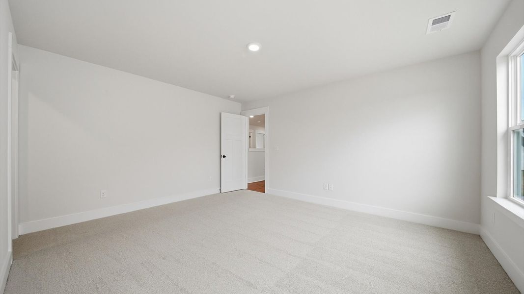 Bright and serene bedroom with comfortable carpeted flooring and large windows for vibrant light at Iris Meadows