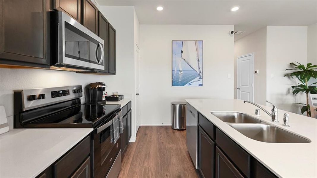 Kitchen featuring stainless steel appliances, dark wood-style floors, light stone counters, and recessed lighting
