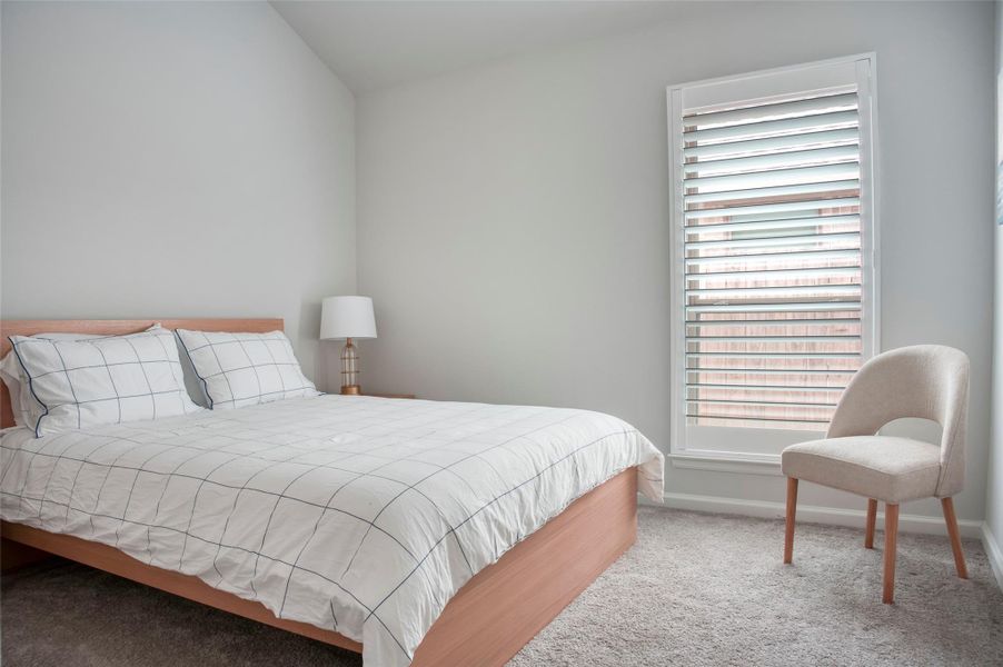 This bedroom features a cozy, minimalist design with a comfortable bed, soft carpeting, and a large window with shutters for natural light. Ideal for relaxation. This bedroom features a cozy, minimalist design with a comfortable bed, soft carpeting, and a large window with shutters for natural light. Ideal for relaxation.