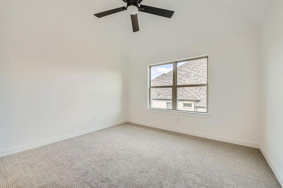 Empty room featuring a towering ceiling, ceiling fan, and carpet flooring