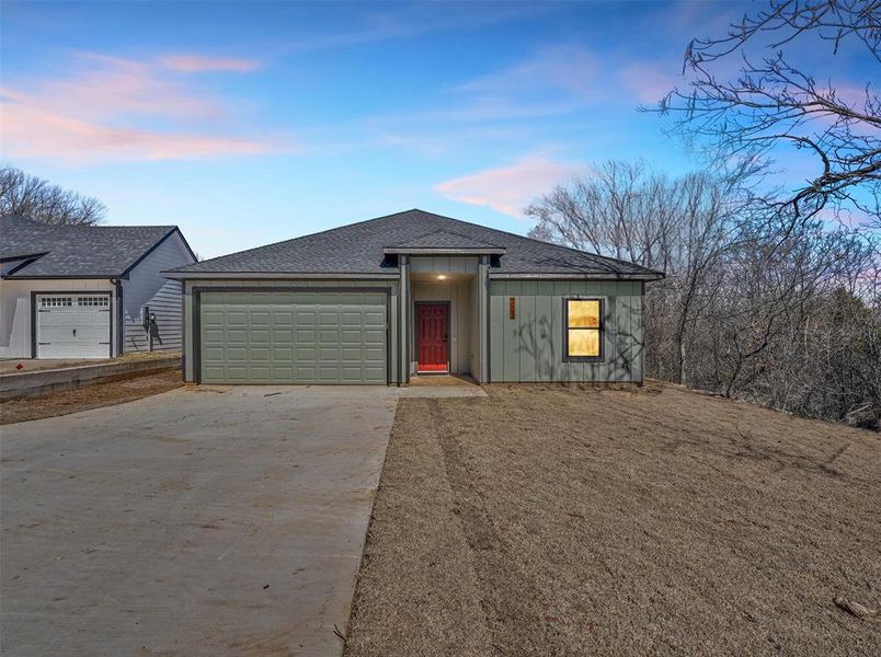 View of front of house featuring an attached garage, concrete driveway, board and batten siding, and a shingled roof