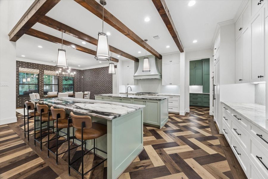 This stunning kitchen was thoughtfully designed to accommodate gatherings of every size while maintaining an elegant, uncluttered appearance. Custom cabinetry conceals premium appliances and dedicated coffee and appliance stations, allowing everyday essentials to remain discreetly organized. Natural stone countertops, custom lighting, touch-activated faucets, multiple sinks, pullout trash systems, and oversized storage drawers reflect the extraordinary attention to detail found throughout.