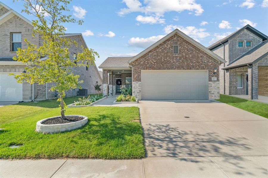 View of front facade featuring driveway, an attached garage, a front yard, and stone siding View of front facade featuring driveway, an attached garage, a front yard, and stone siding