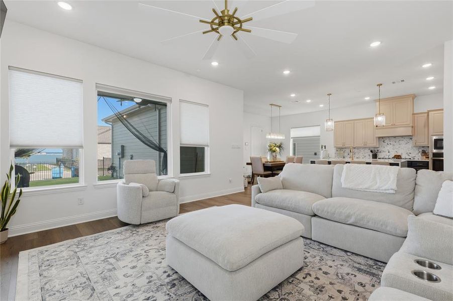 Open-concept living area featuring wood-finish flooring, recessed lighting, and a modern ceiling fan Open-concept living area featuring wood-finish flooring, recessed lighting, and a modern ceiling fan