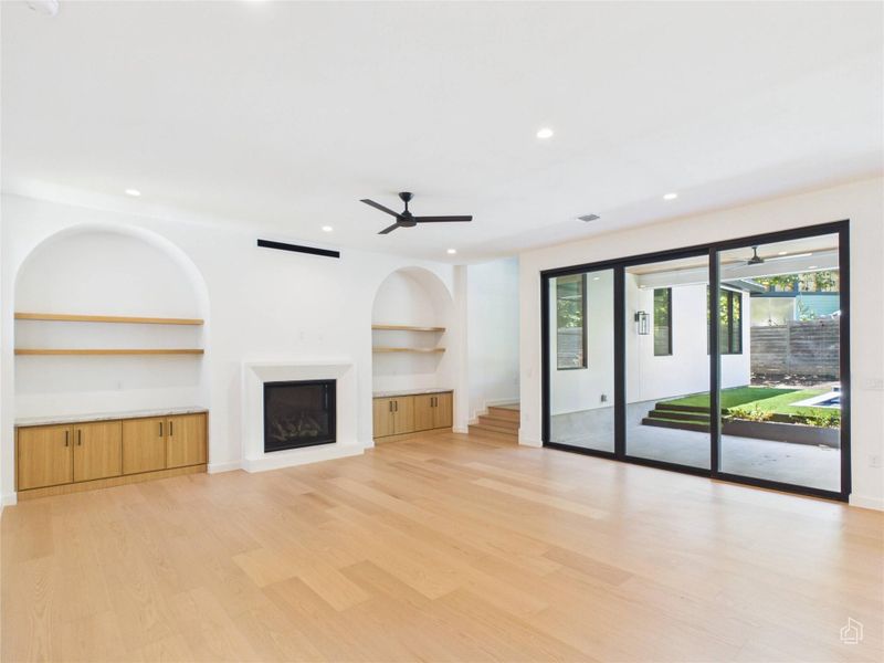 Hardwood floors and built-in shelving complement the modern fireplace in this open living area.