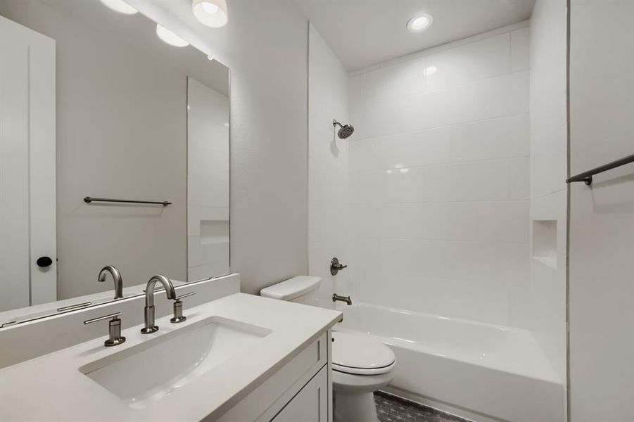 Bathroom featuring a vanity with an integrated sink, brushed nickel fixtures, a full-width mirror, a tiled shower-tub combination, and recessed lighting