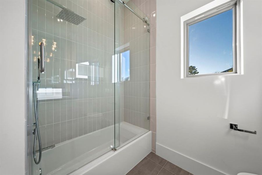 Bathroom 4 features a modern tub-shower combo with a frameless glass enclosure and sleek vertical tile design, creating a clean and stylish look. The rainfall showerhead adds a luxurious touch, while the bright window brings in natural light to enhance the space. Perfectly crafted for comfort and functionality, this bathroom is both elegant and practical.