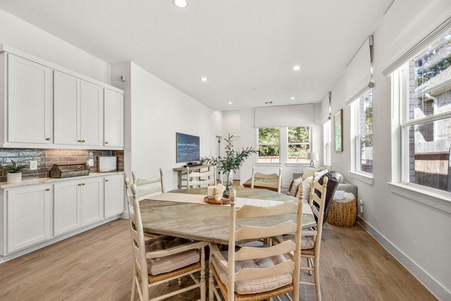 This bright and airy open-concept living space features a modern kitchen and a dining area that flows into a cozy living room. Large windows provide ample natural light, and the wooden flooring adds a warm touch. This bright and airy open-concept living space features a modern kitchen and a dining area that flows into a cozy living room. Large windows provide ample natural light, and the wooden flooring adds a warm touch.