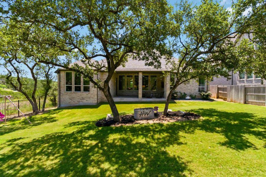 A spacious, verdant yard with mature trees frames a well-appointed rear patio perfect for outdoor living.