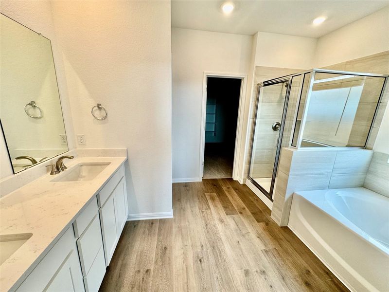 Bathroom featuring a shower stall, double vanity, a bath, and light wood finished floors