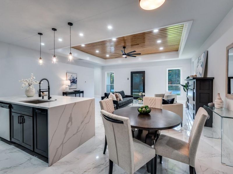 Dining space with a tray ceiling, light marble finish flooring, and recessed lighting.