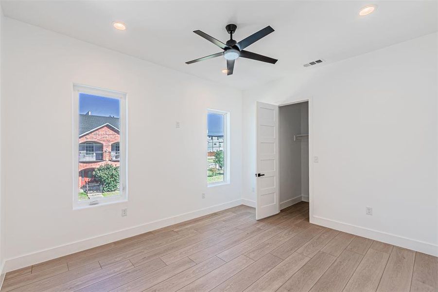 Unfurnished bedroom featuring a spacious closet, a ceiling fan, light wood-style floors, and recessed lighting