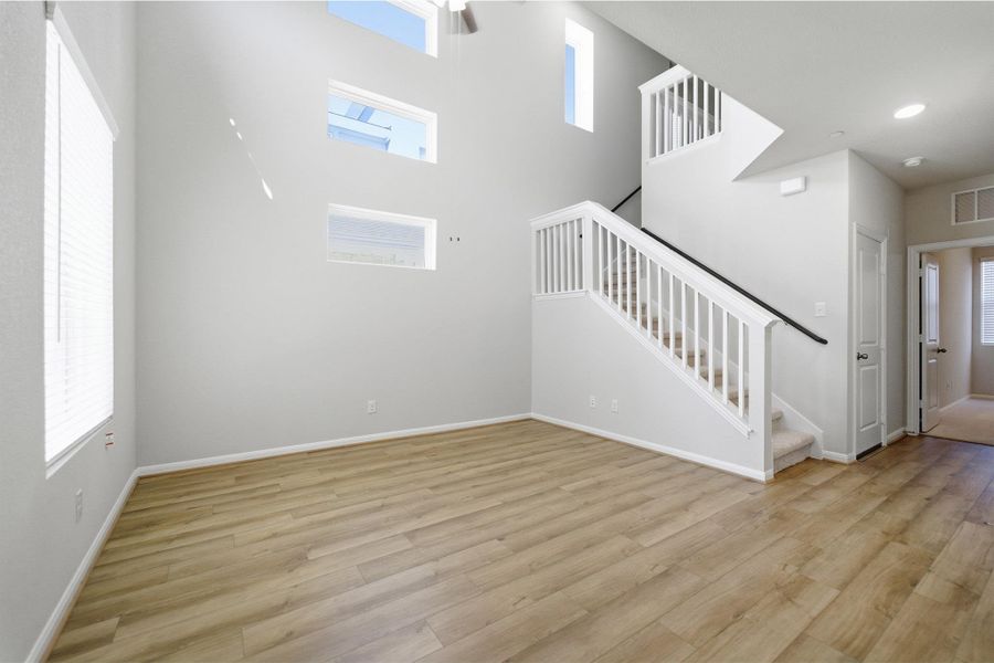 Unfurnished living room with light wood-style floors and a high ceiling