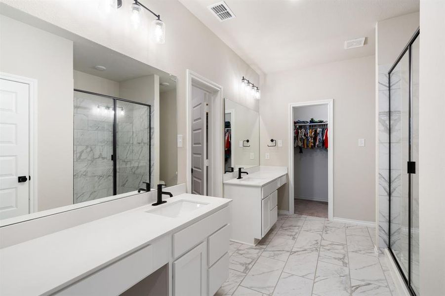 Bathroom with a spacious closet, a marble finish shower, two vanities, and light marble finish floors Bathroom with a spacious closet, a marble finish shower, two vanities, and light marble finish floors
