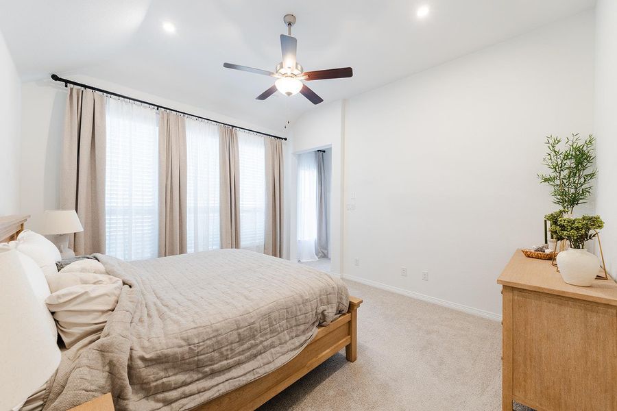 Bedroom featuring light colored carpet, ceiling fan, and vaulted ceiling