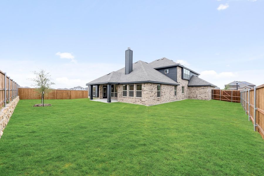 Brick home rear exterior with large fenced backyard, covered patio, and chimney Brick home rear exterior with large fenced backyard, covered patio, and chimney