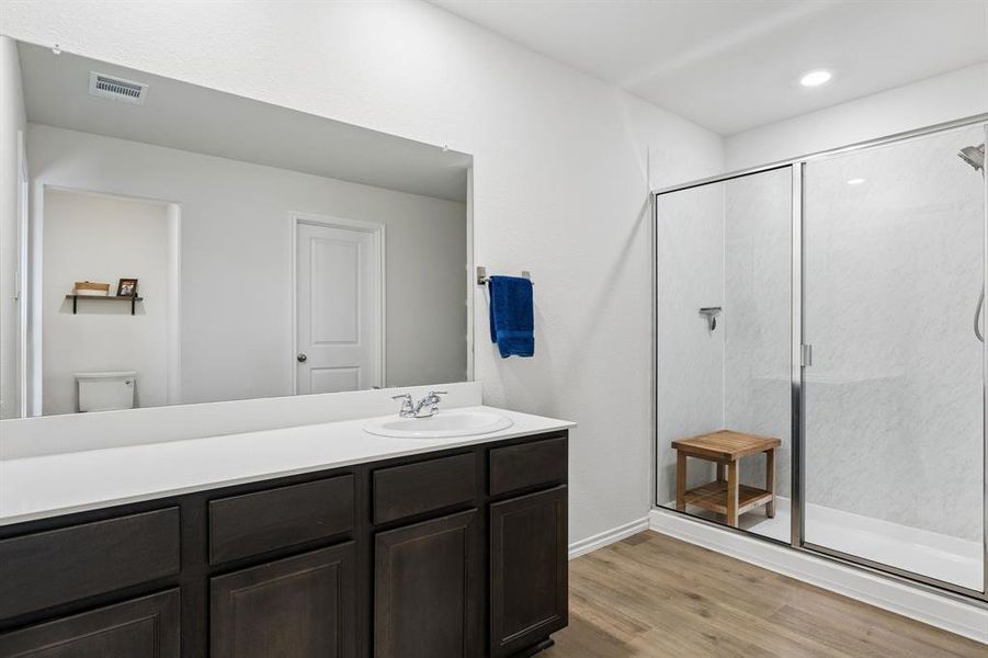 Full bath with a marble finish shower, vanity, light wood finished floors, and recessed lighting Full bath with a marble finish shower, vanity, light wood finished floors, and recessed lighting
