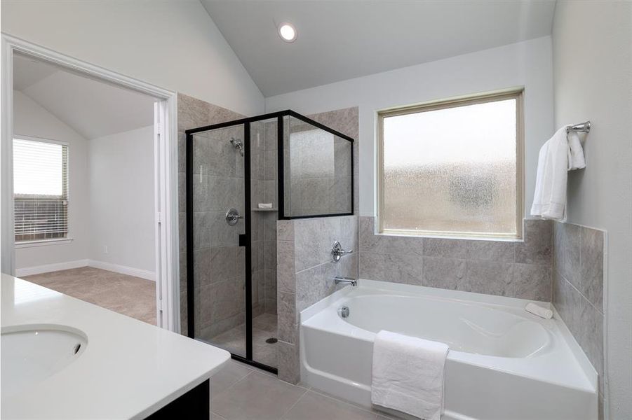 Full bathroom featuring lofted ceiling, tile patterned floors, vanity, a bath, and a stall shower