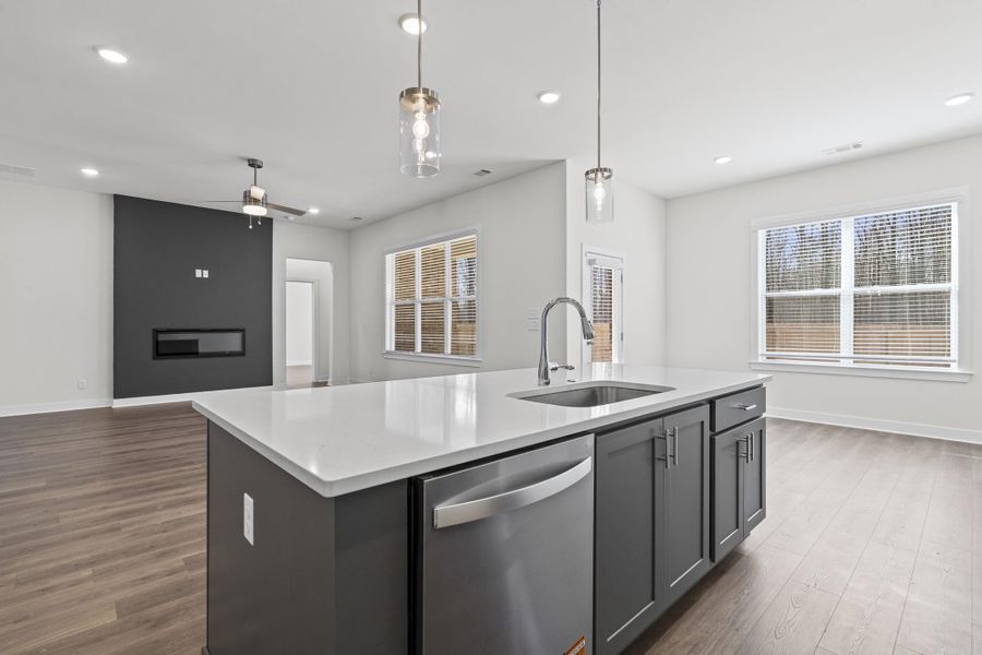 Kitchen with stainless steel dishwasher, a kitchen island with sink, open floor plan, decorative light fixtures, and ceiling fan