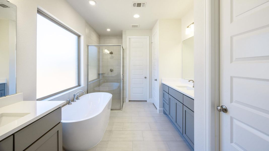 Bathroom featuring a freestanding tub, a stall shower, recessed lighting, light tile patterned floors, and two vanities Bathroom featuring a freestanding tub, a stall shower, recessed lighting, light tile patterned floors, and two vanities