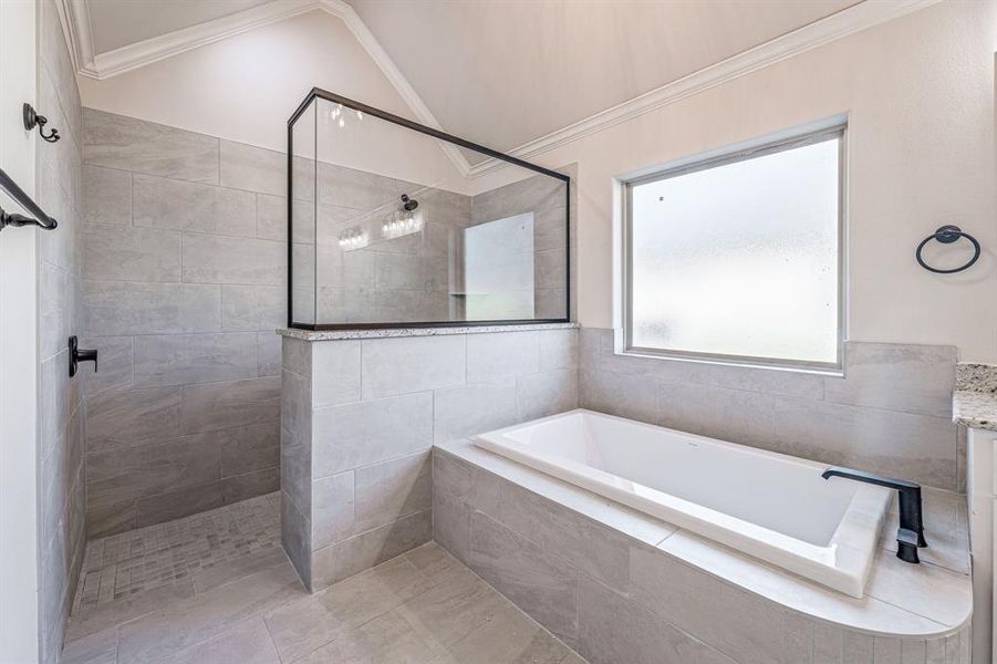 Bathroom featuring walk in shower, crown molding, a garden tub, and vaulted ceiling
