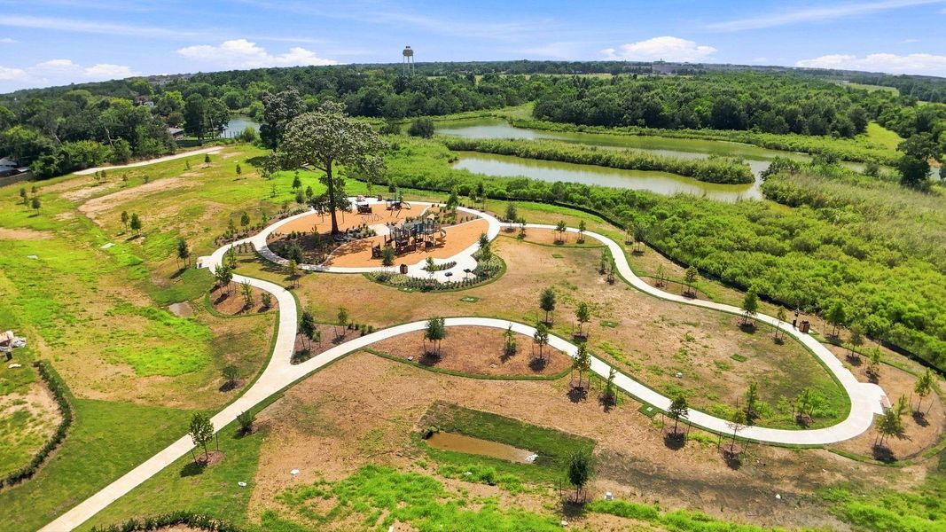 Community playground with swings, slides, and a shaded seating area surrounded by green space Community playground with swings, slides, and a shaded seating area surrounded by green space